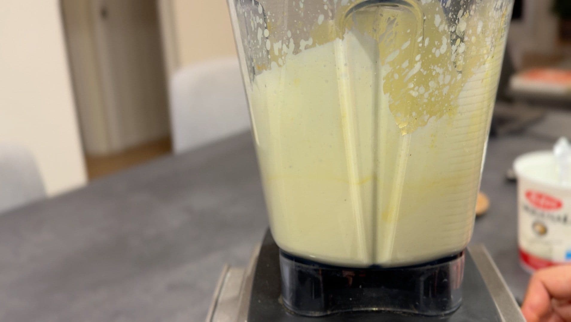 Blended yogurt and saffron mixture in a food processor with a pale yellow color and smooth texture.