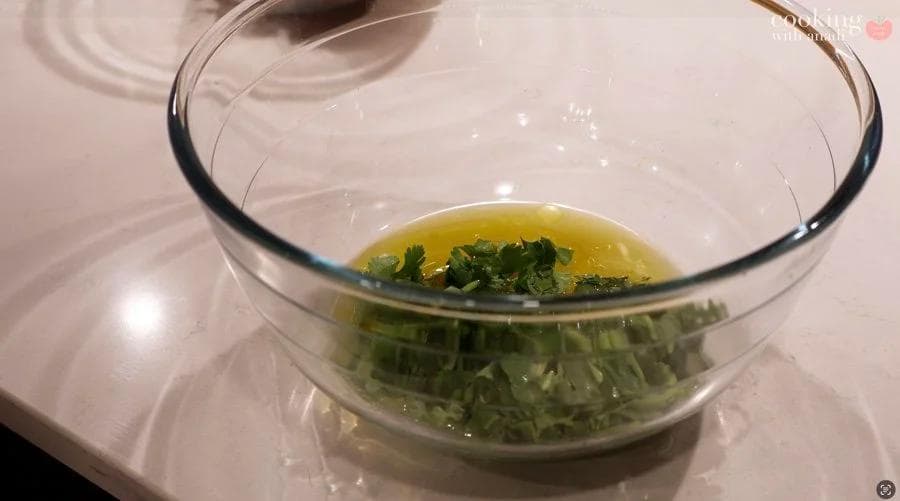 Mojo marinade with garlic, citrus, olive oil, and cilantro whisked together in a glass bowl