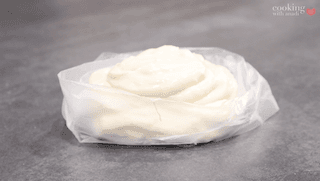 Creamy white glaze piped into a decorative swirl inside a piping bag lined with parchment paper.