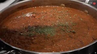 Dal Makhani simmering in a pot with crushed kasoori methi sprinkled on top of the creamy tomato lentil curry.