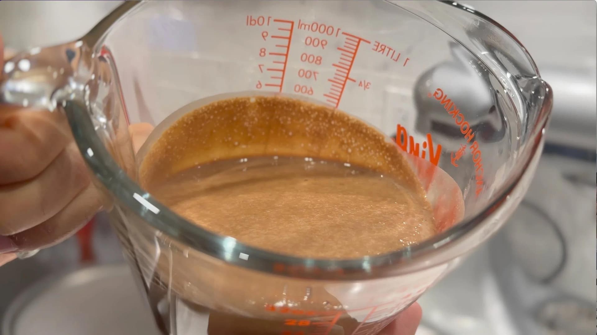 Chocolate crepe batter in a glass measuring cup, ready to be poured onto a pan.