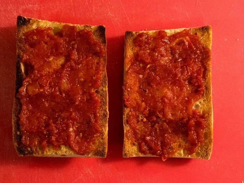 Two slices of toasted ciabatta bread with crispy golden edges on a red background.