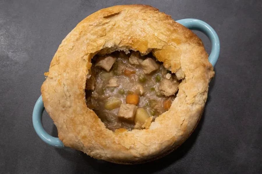St. Patrick's Day Guinness chicken pot pie with golden pastry crust and savory filling visible through opening.