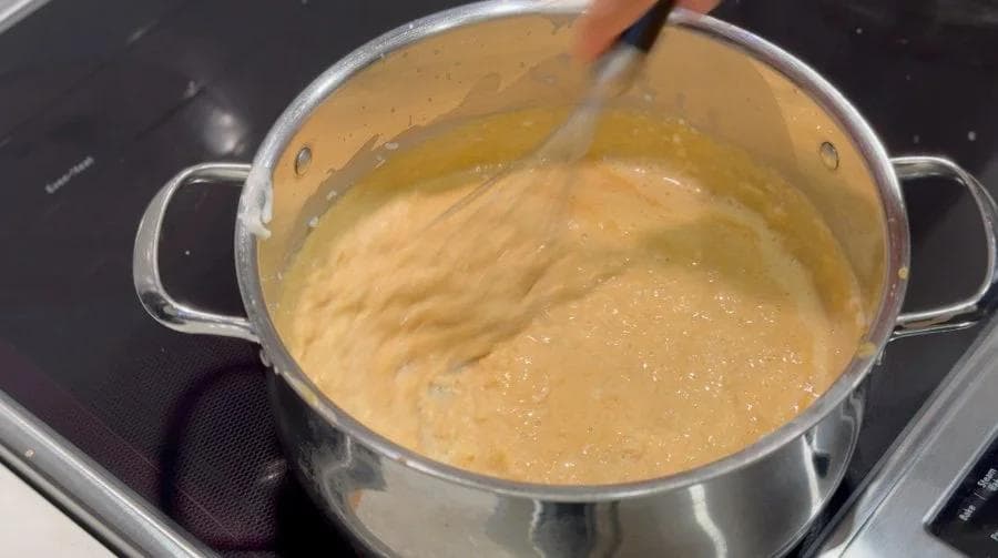 Creamy pumpkin rice pudding mixture being stirred in a pot on the stovetop.