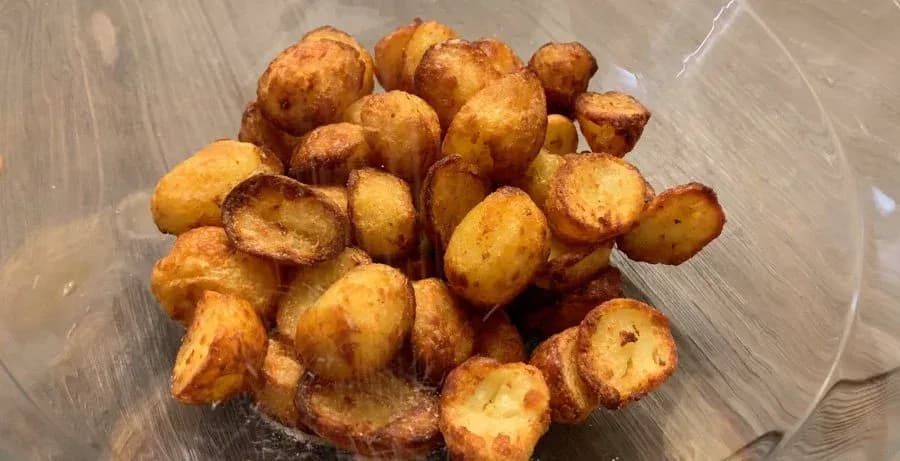 Golden brown and crispy air-fried baby potatoes in a clear bowl, ready to be seasoned and served.