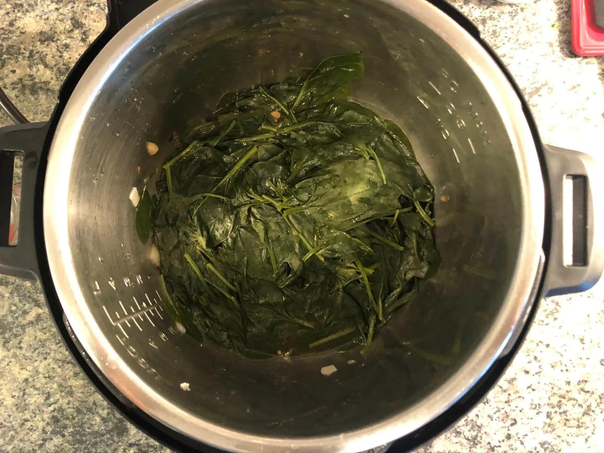 Cooked spinach in an Instant Pot with a dark, overcooked appearance due to prolonged cooking time.