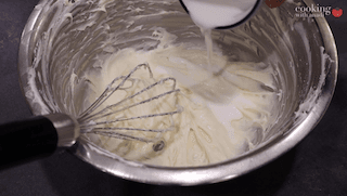 Milk being poured into a bowl of powdered sugar glaze with a whisk, for sugar cookie waffle topping.