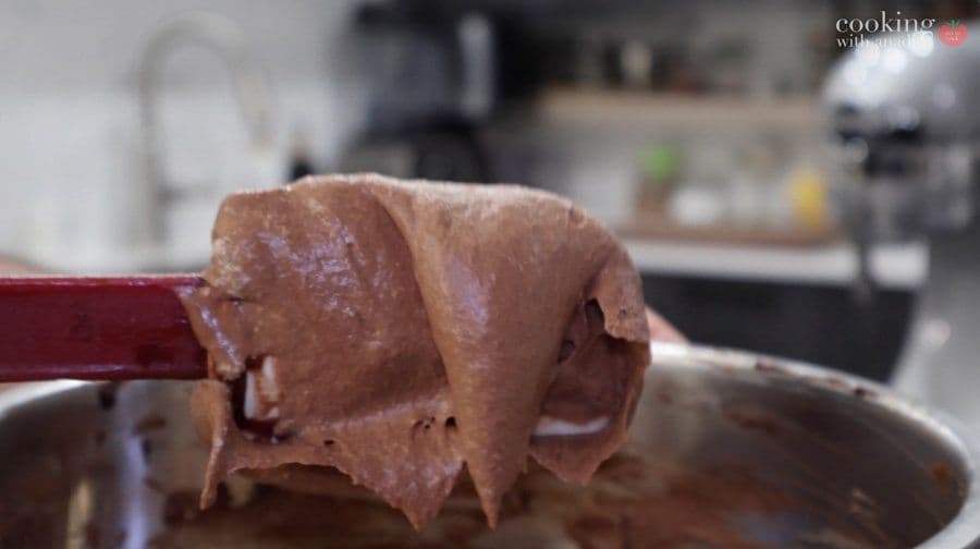 Chocolate mousse being folded with a spatula, showing the light, airy texture of the whipped mixture.