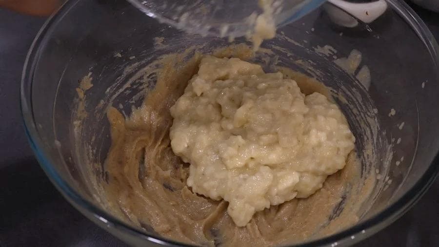 Wet ingredients including mashed bananas, milk, and molasses mixed into butter and sugar in a bowl.