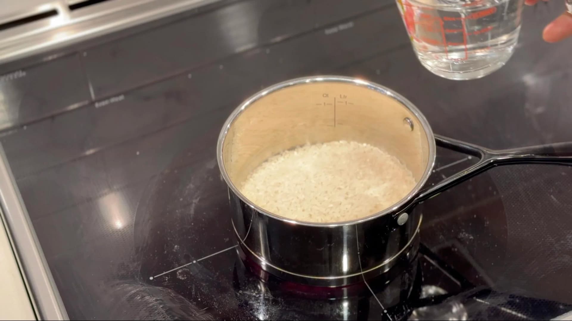 Cooked white sushi rice in a saucepan on a stovetop burner, ready for seasoning.