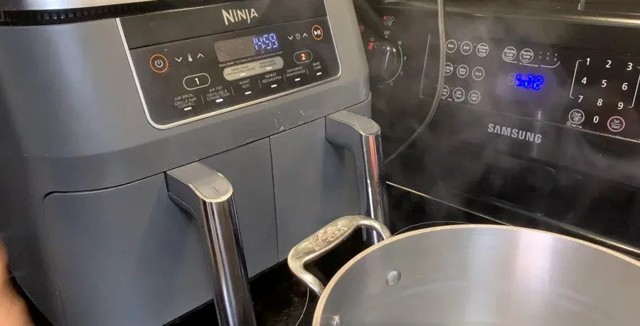 Ninja air fryer set to 400F next to a pot and Samsung microwave in a kitchen.