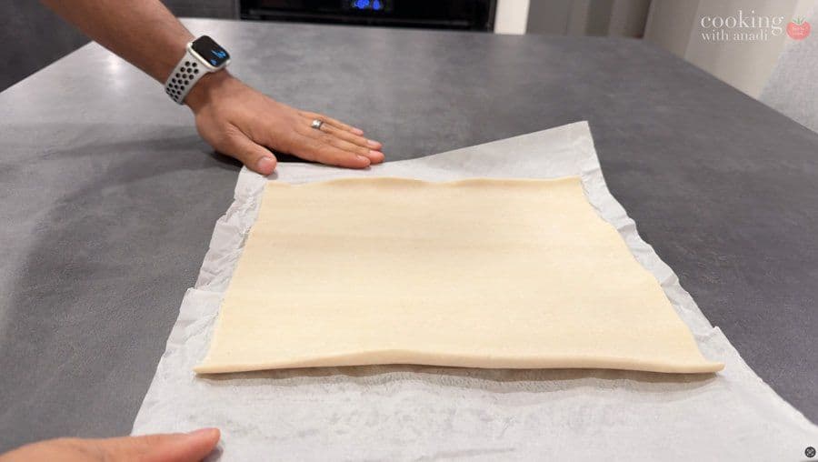 Unbaked puff pastry square with potato filling in the center, ready to be folded into a turnover.
