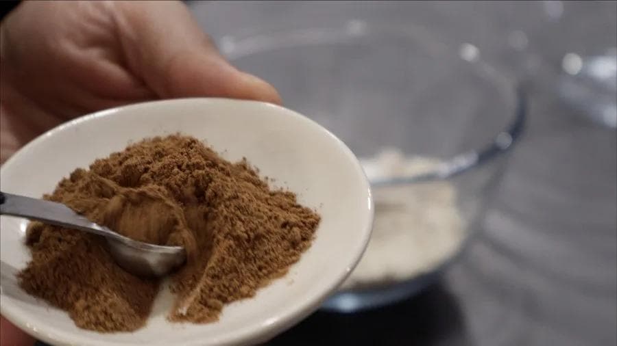 Dry ingredients for pumpkin spice cookies mixed in a white bowl with a spoon, including protein powder and oat flour.