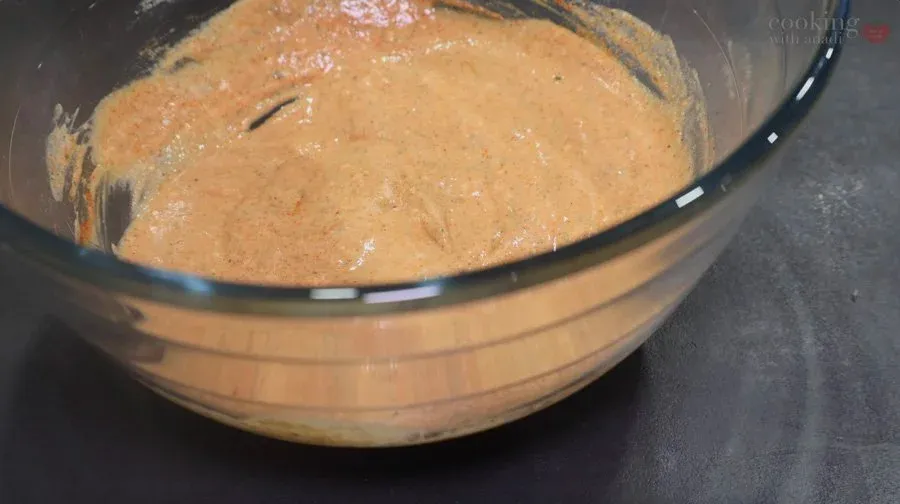 Creamy yogurt-based marinade in a bowl with a whisk, ready for paneer and vegetables.