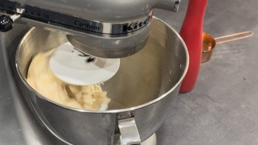 KitchenAid mixer with dough hook kneading pizza dough in stainless steel bowl