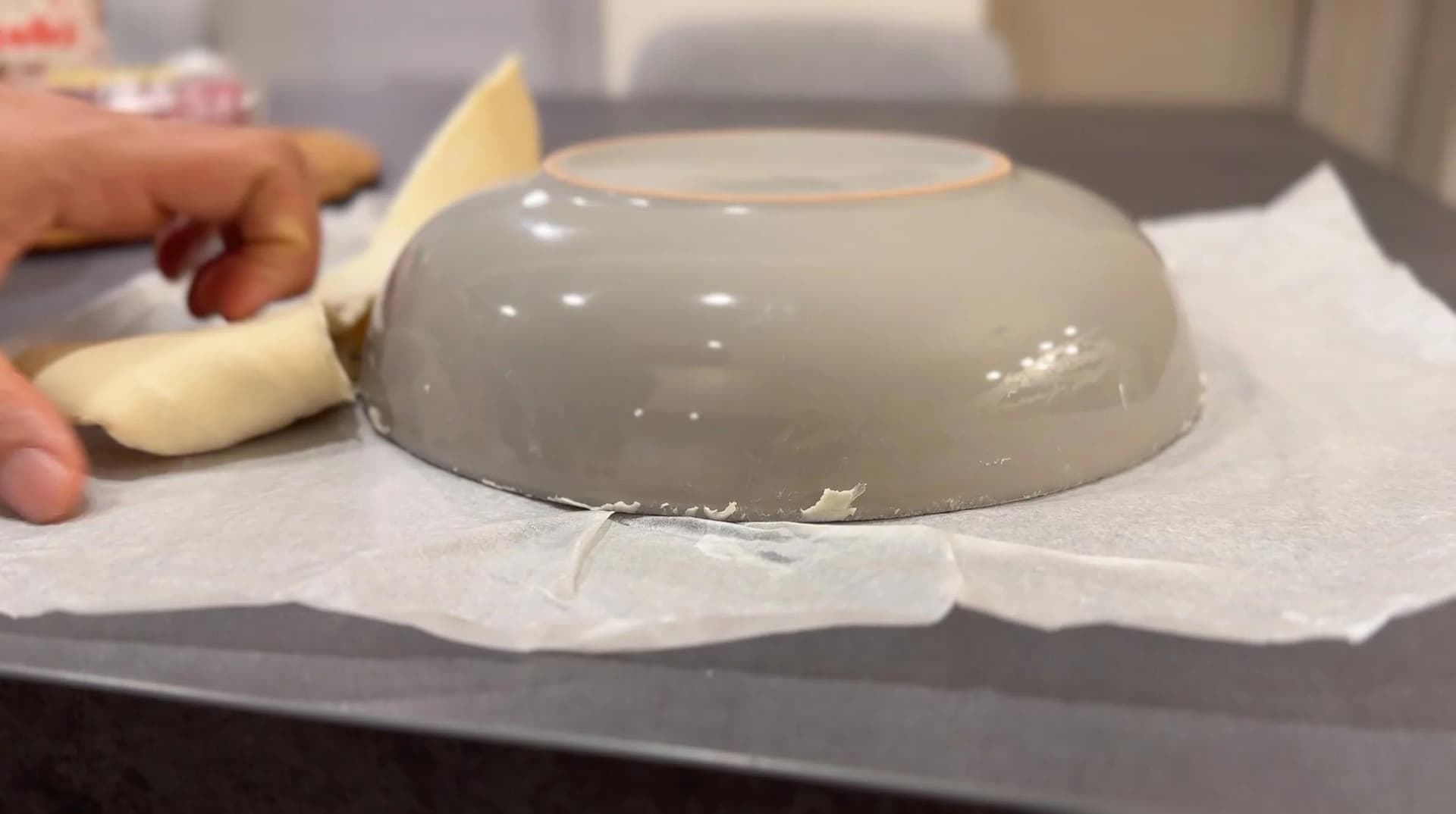 Gray ceramic bowl inverted over parchment paper on baking sheet with sliced banana nearby.