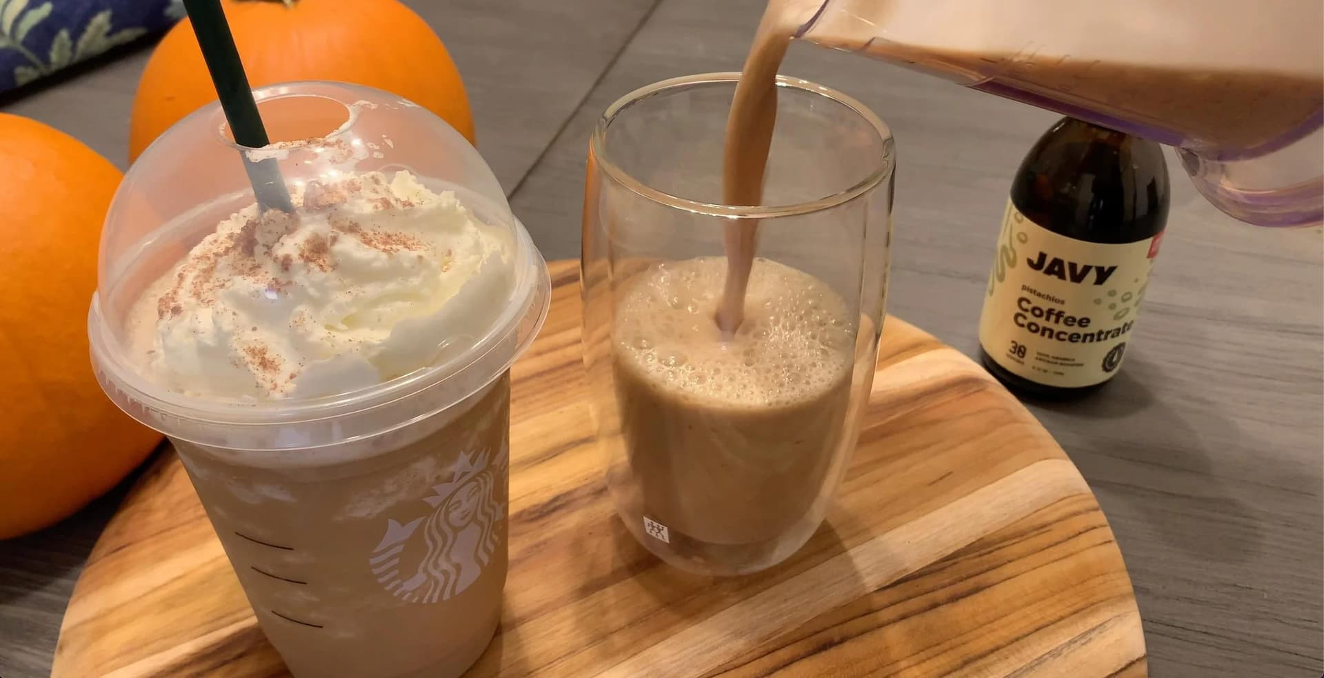 Blended pumpkin spice frappuccino being poured into a glass next to a Starbucks cup and javy coffee concentrate.