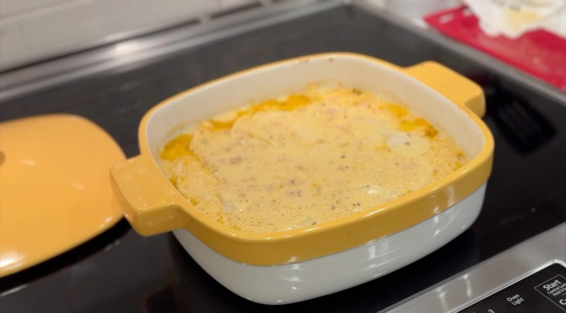 Baked scalloped potatoes in a yellow casserole dish with creamy sauce, fresh from the oven.