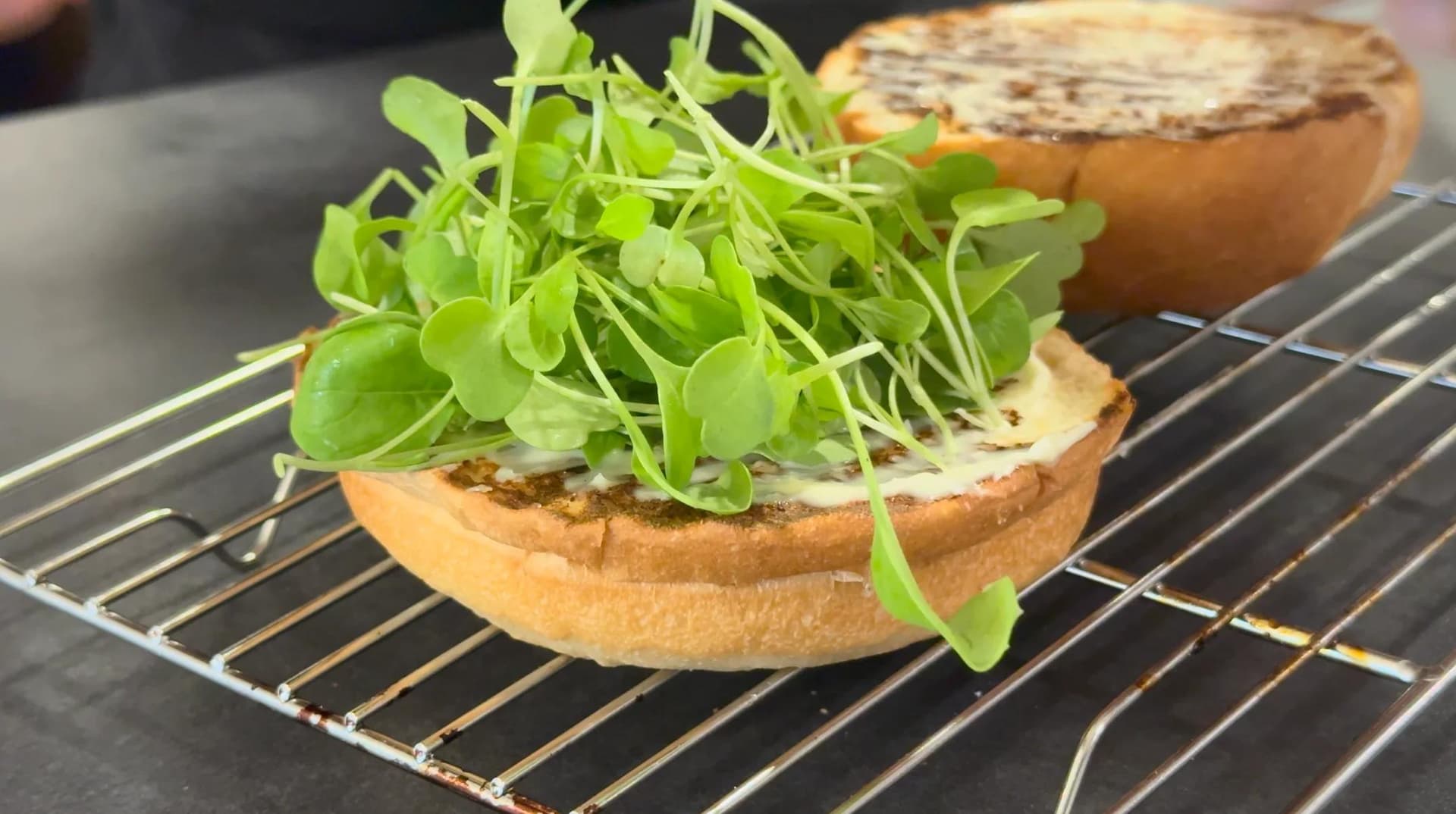 Spinach turkey burger on toasted bun topped with fresh arugula microgreens and spread.