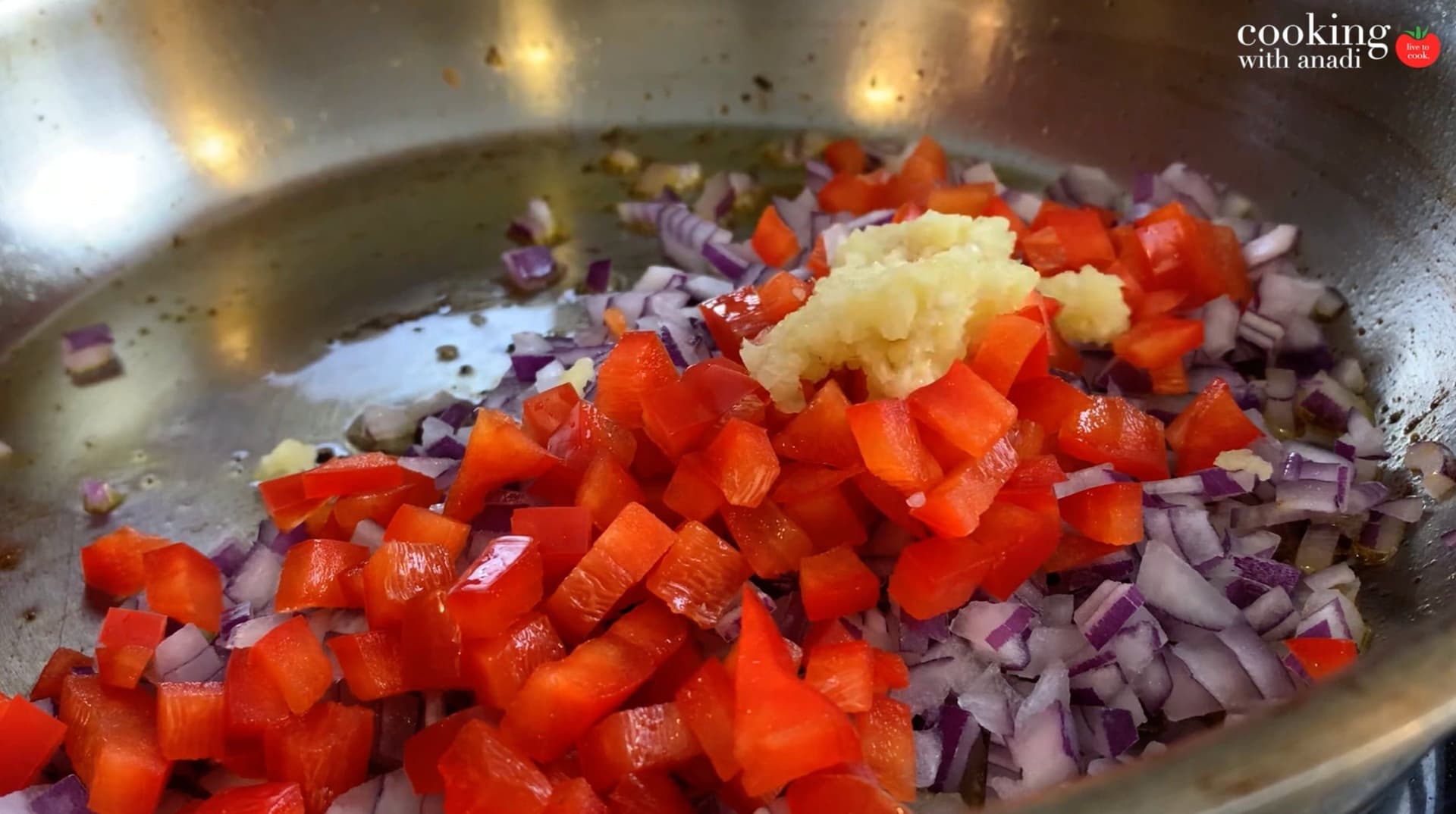 Sautéed red peppers, purple onions, and minced garlic in a stainless steel pan during the vegetable cooking step.