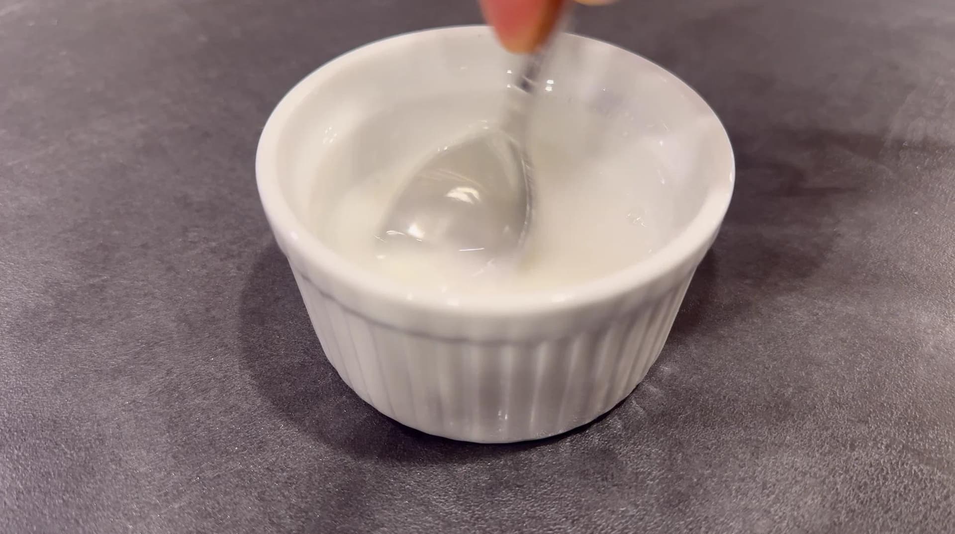 Cornstarch slurry being stirred into gravy in a white bowl with a spoon