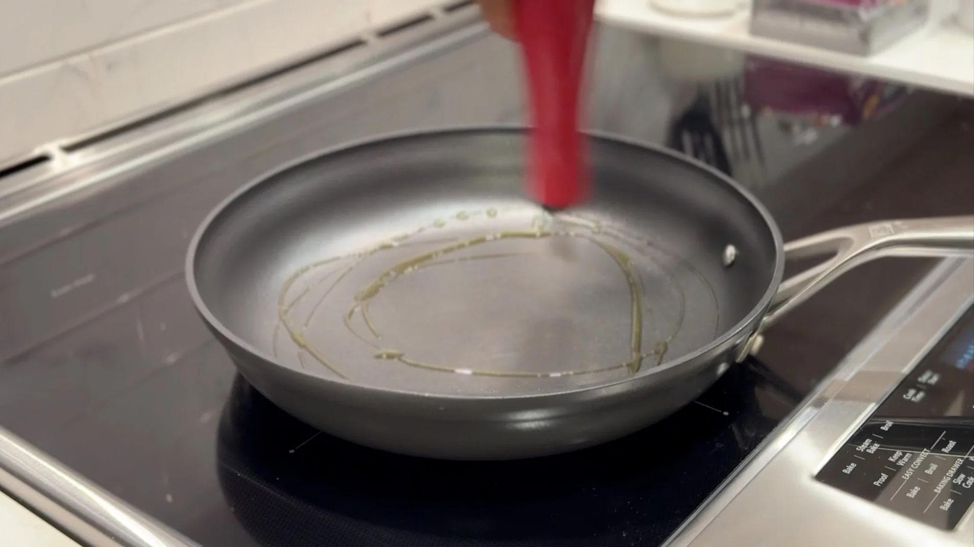 Olive oil swirling in a stainless steel pan on an induction cooktop, ready for cooking mushrooms.
