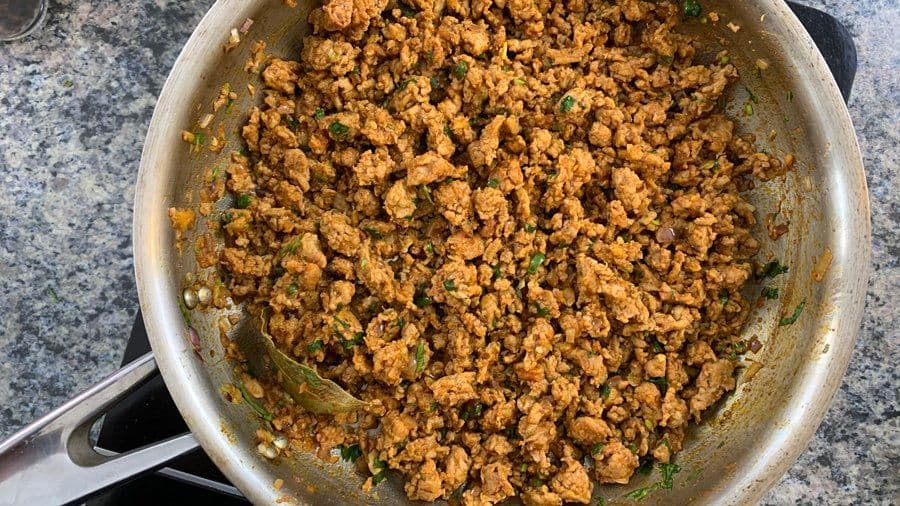 Cooked ground chicken keema with spices and cilantro garnish in a stainless steel skillet