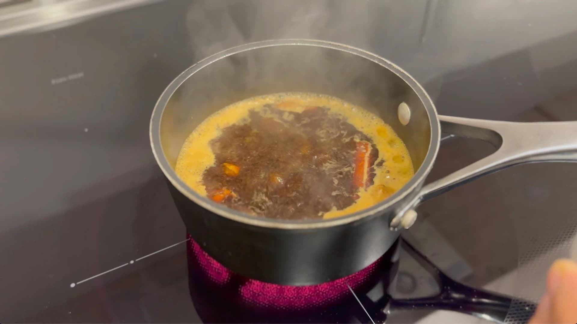 Turmeric chai latte simmering in a saucepan with milk and spices on the stovetop.