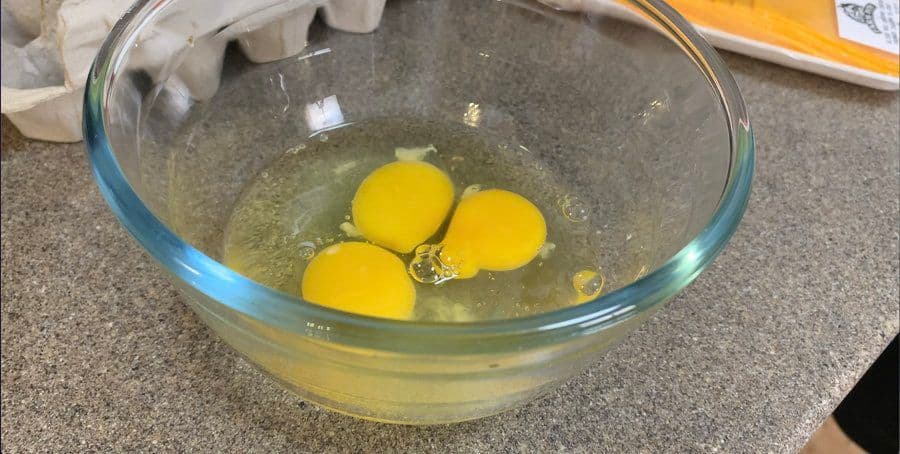 Three whisked eggs with salt and pepper in a glass bowl, ready to be cooked for the omelette.