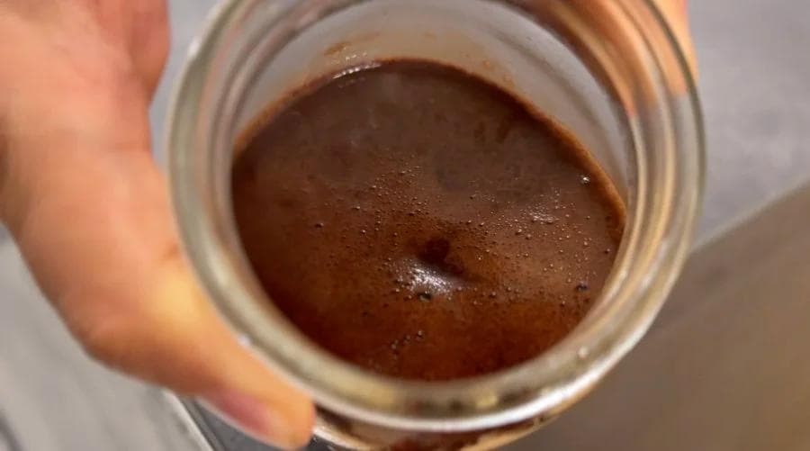 Homemade chocolate sauce in a mason jar, smooth and glossy brown consistency.