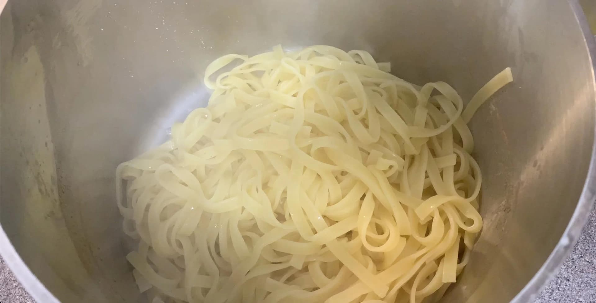 Cooked pasta noodles in a white pot, ready to be served with coq au vin stew.