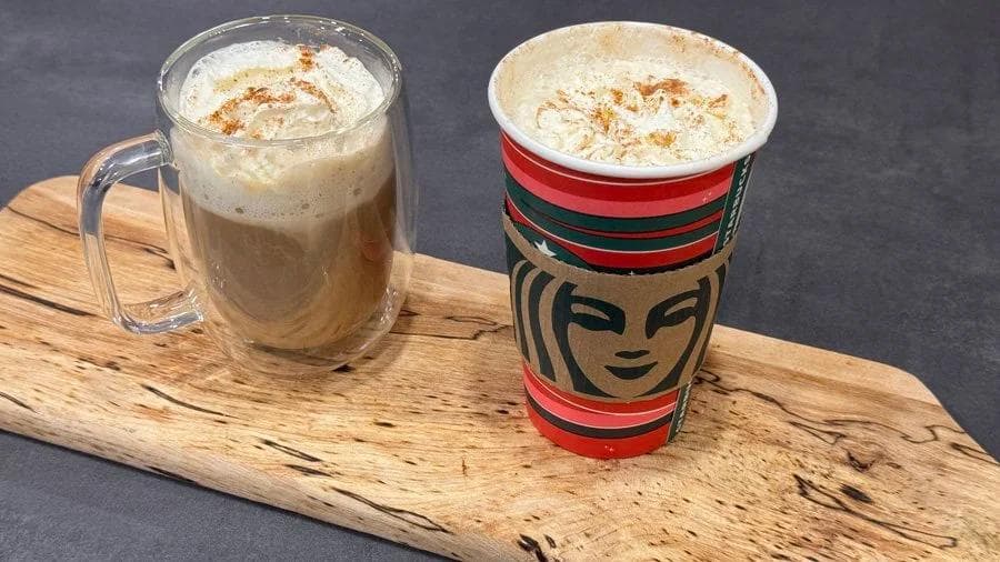 Two gingerbread lattes with whipped cream and cinnamon garnish displayed on a wooden board.