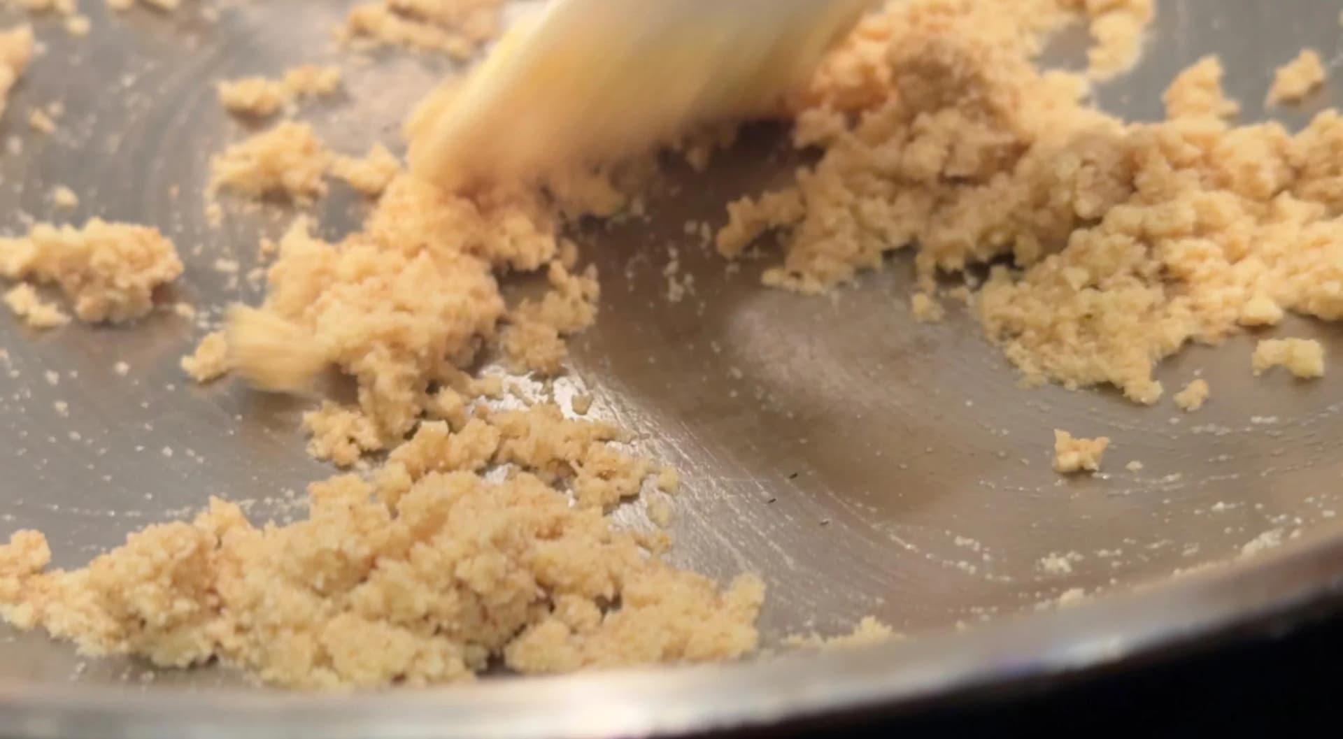 Golden semolina being stirred and roasted in a pan until it turns brown.