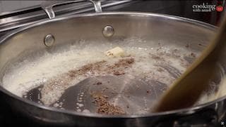 Ghee and cumin seeds sizzling in a pan during tadka preparation for dal makhani.