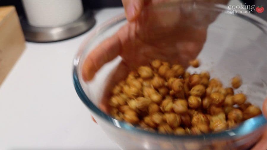 Hot air fryer chickpeas being transferred to a bowl for seasoning, golden and crispy.