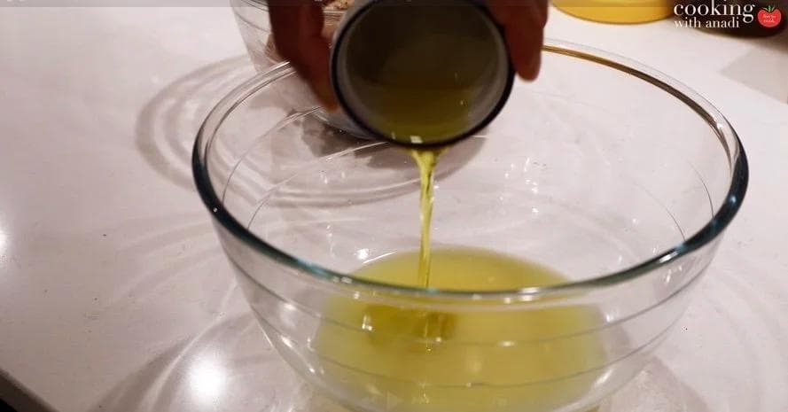 Pouring olive oil into a bowl of mojo marinade made with garlic, citrus juice, and cilantro.