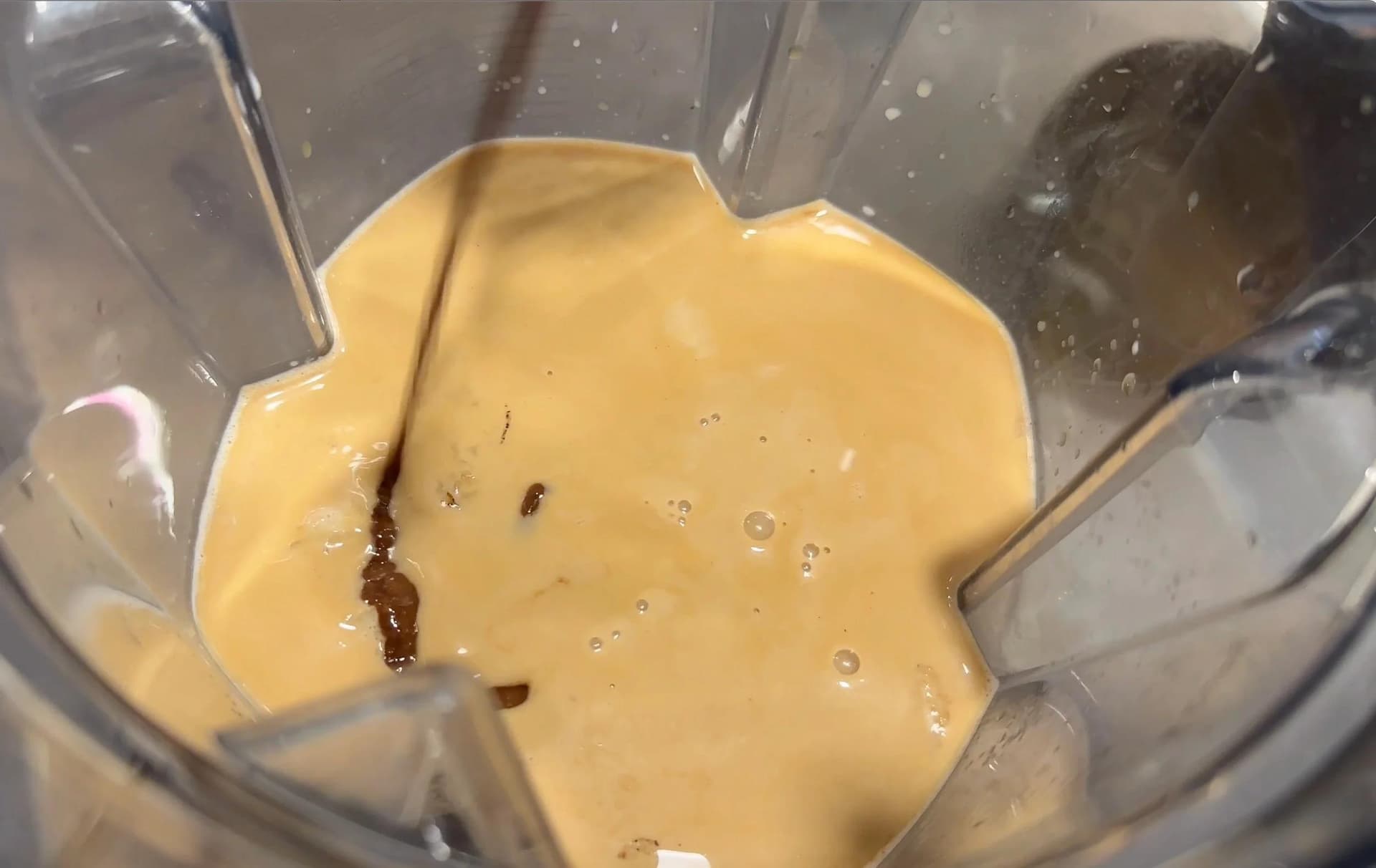 Creamy banana mocha frappe mixture blended in a food processor, ready to pour.