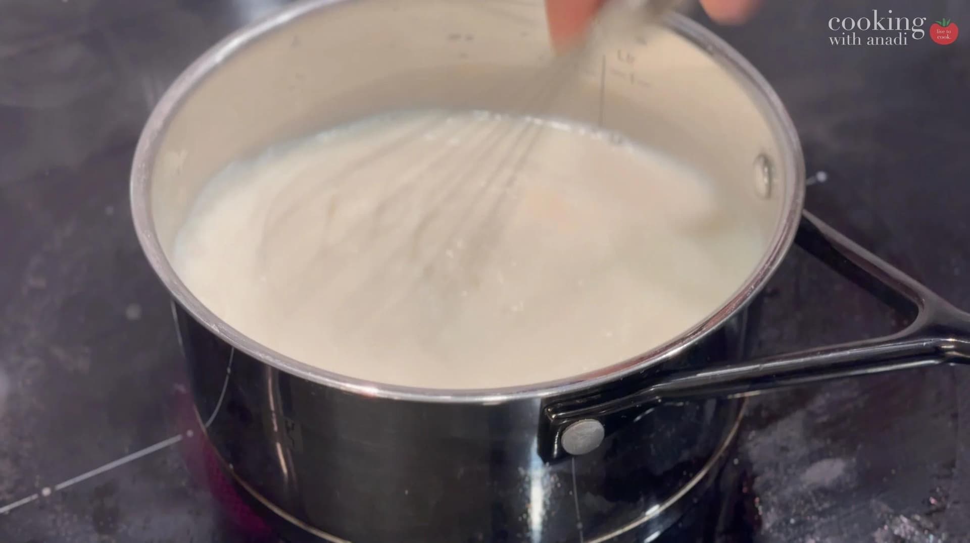 Strained milk with sugar and salt being stirred in a saucepan on the stovetop.