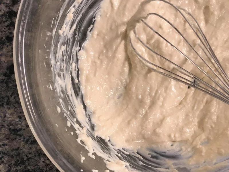 Creamy Greek yogurt Caesar dressing being whisked in a glass bowl until smooth and well combined.