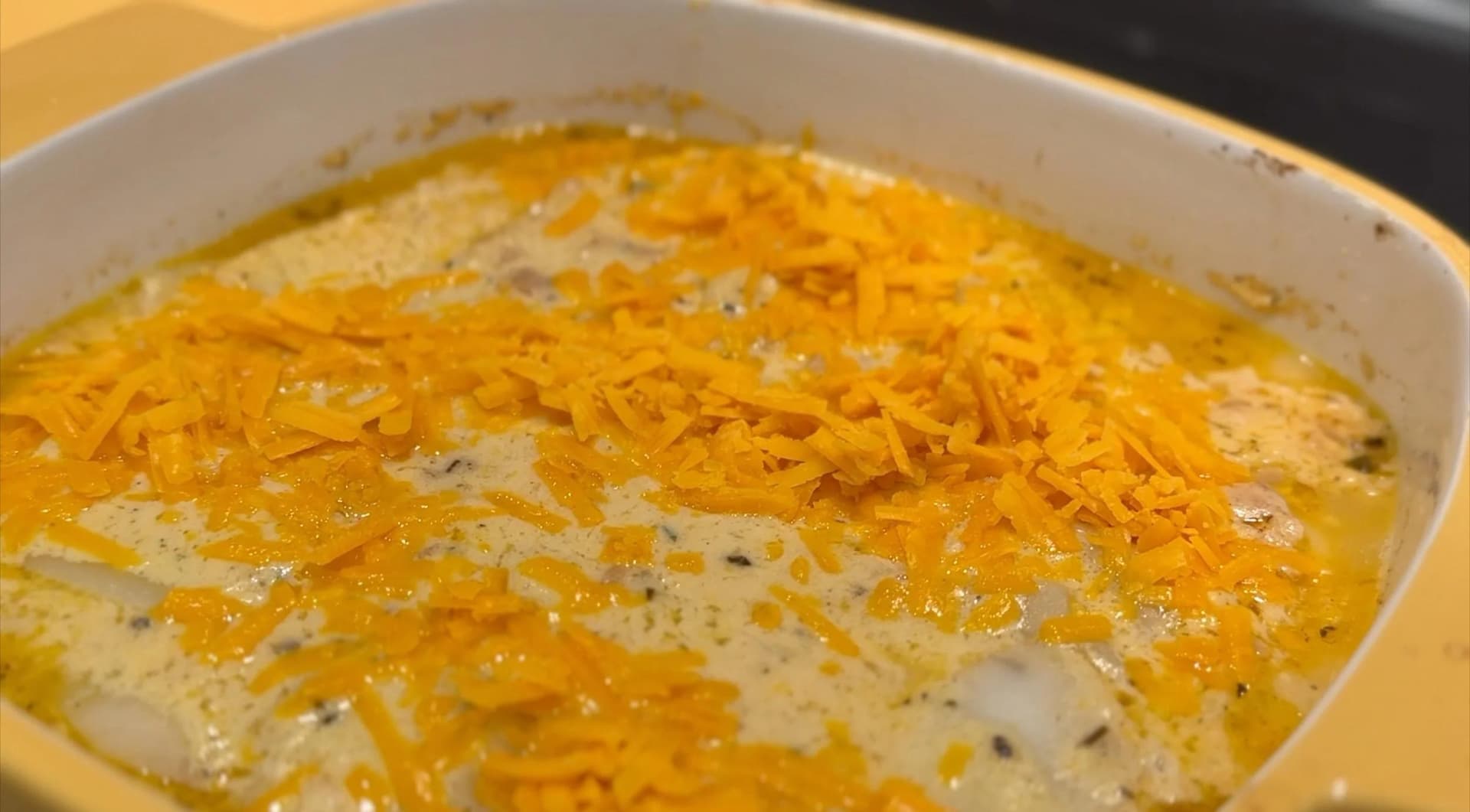 Baked scalloped potatoes with melted cheese topping and black pepper in a white casserole dish.