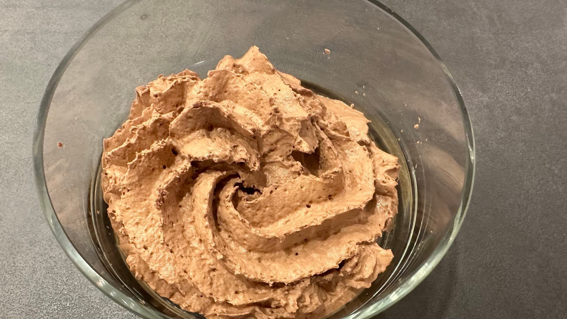 Chocolate whipped cream in a glass bowl with swirled texture and peaks