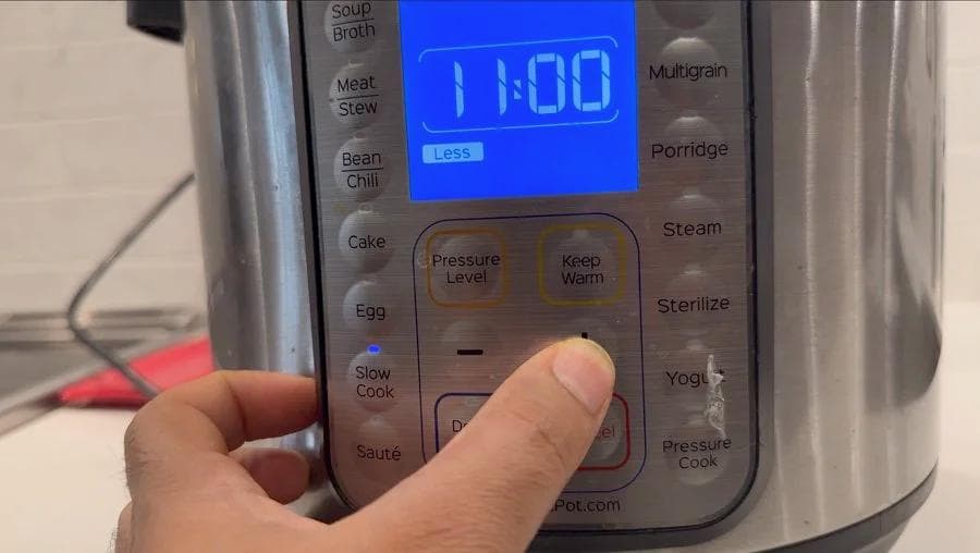 Hand adjusting Instant Pot timer to 11 hours on low pressure setting for slow cooking birria.