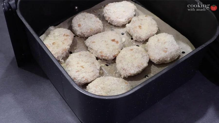 Golden breaded chicken nuggets arranged in an air fryer basket before cooking.
