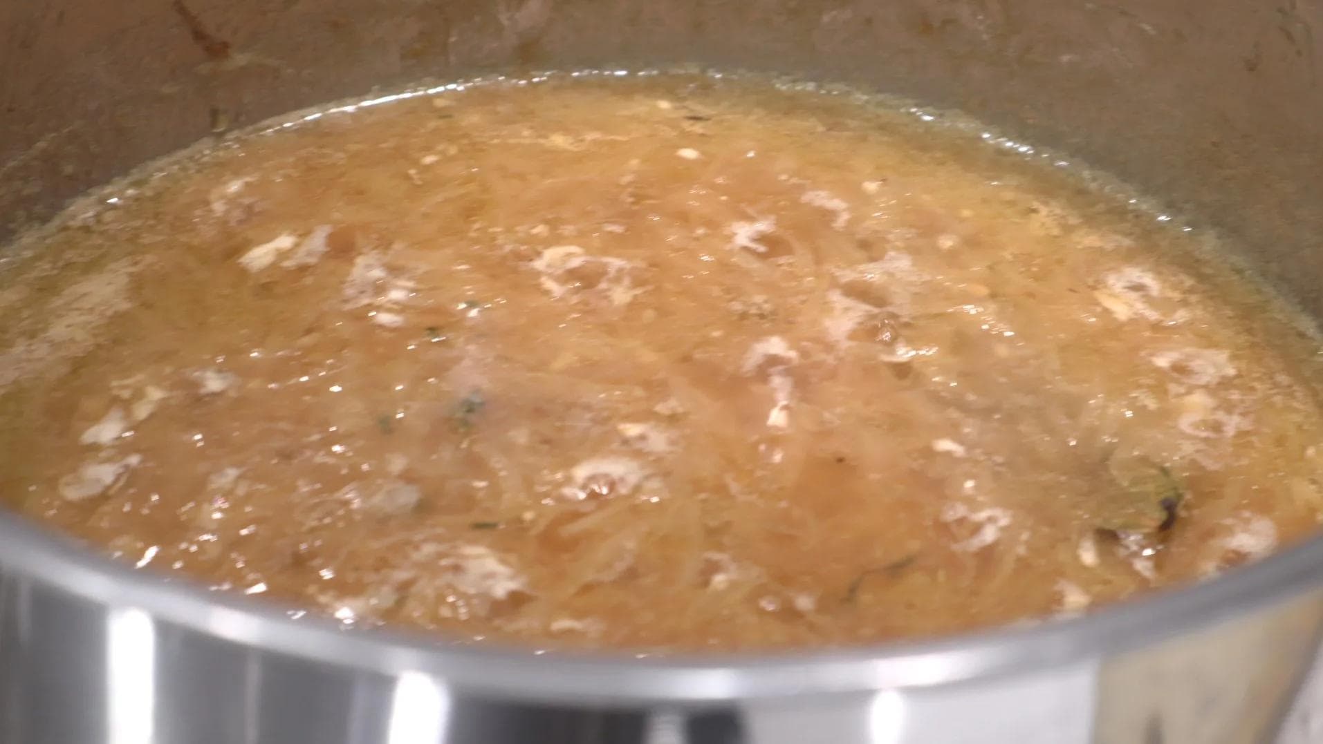 French onion soup simmering in a pot with caramelized onions and broth.