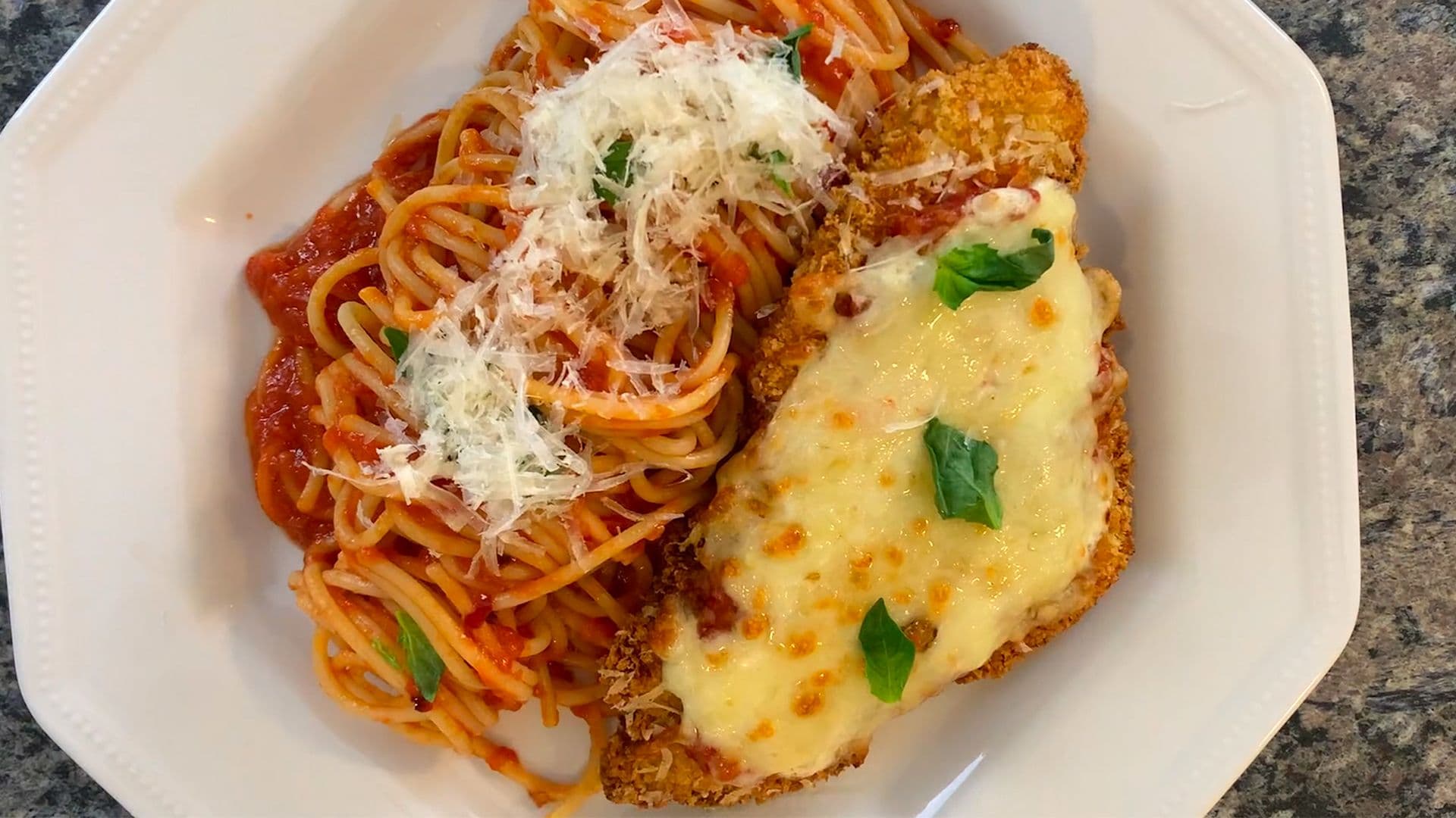 Crispy air fryer chicken parmesan with melted cheese and marinara sauce, served with spaghetti on a white plate.
