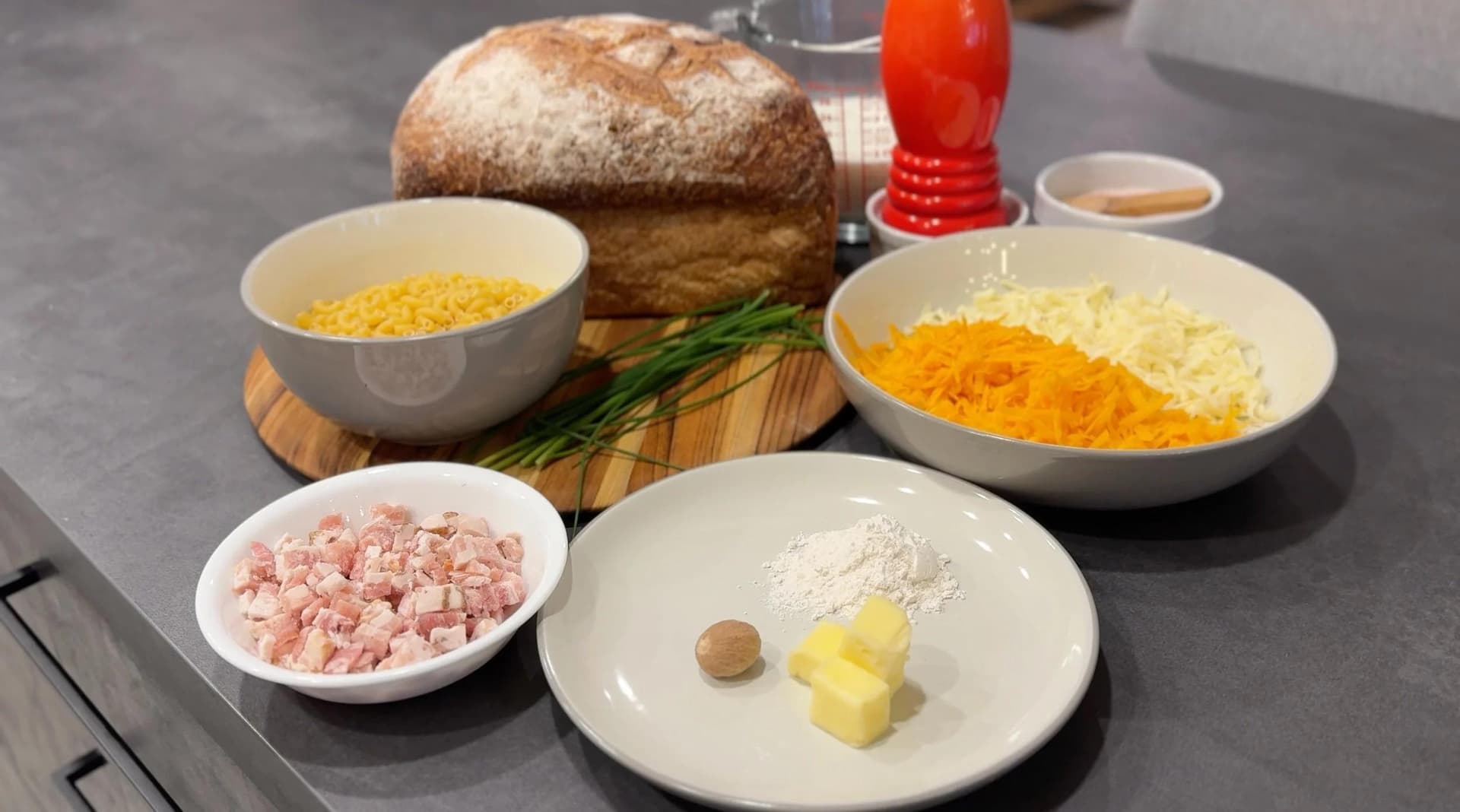 Ingredients for Mac and Cheese Grilled Cheese laid out: bread, elbow macaroni, shredded cheddar and white cheese, diced ham, butter, and seasonings.