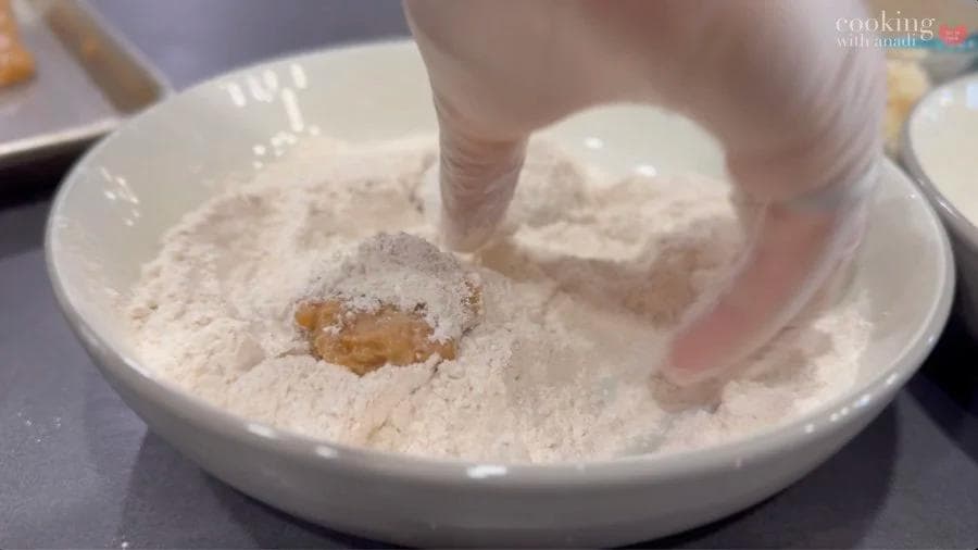 Chicken nugget being coated in breadcrumbs for air fryer cooking.