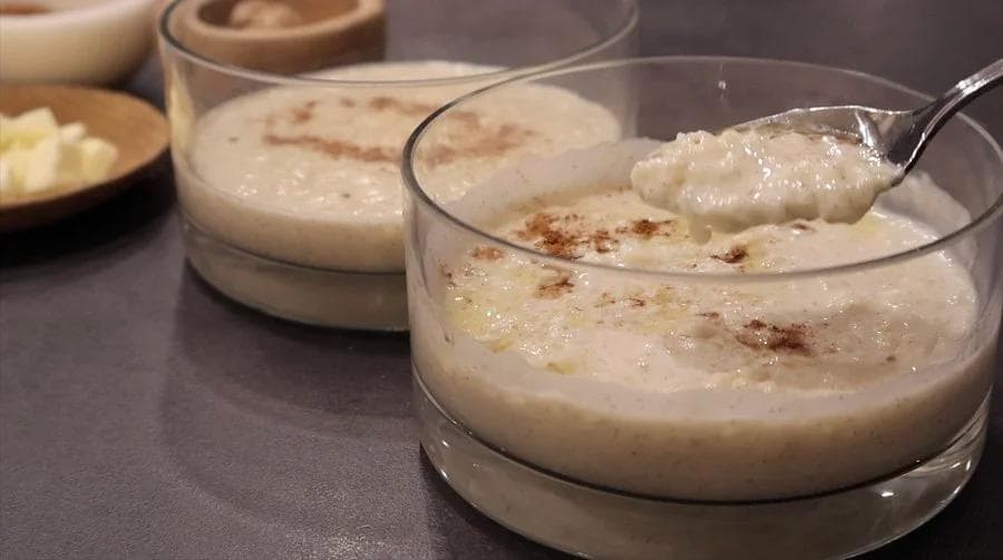 Creamy Southern rice pudding in glass bowls topped with cinnamon, one with a spoon.