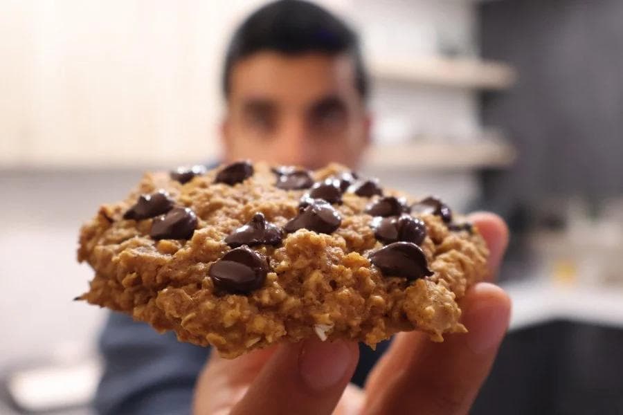 Hand holding a high protein pumpkin chocolate chip cookie with chocolate chips on top