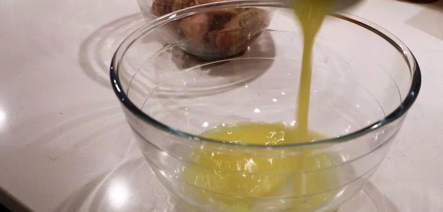Olive oil-based mojo marinade being poured into a glass bowl with garlic and citrus marinade ingredients.